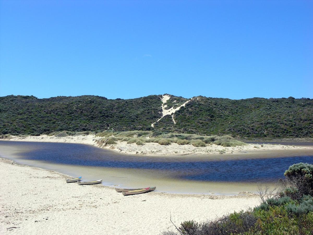 The Margaret River lagoon behind the sand bar at the river mouth near Prevelly, Western Australia, with hire canoes on the beach
