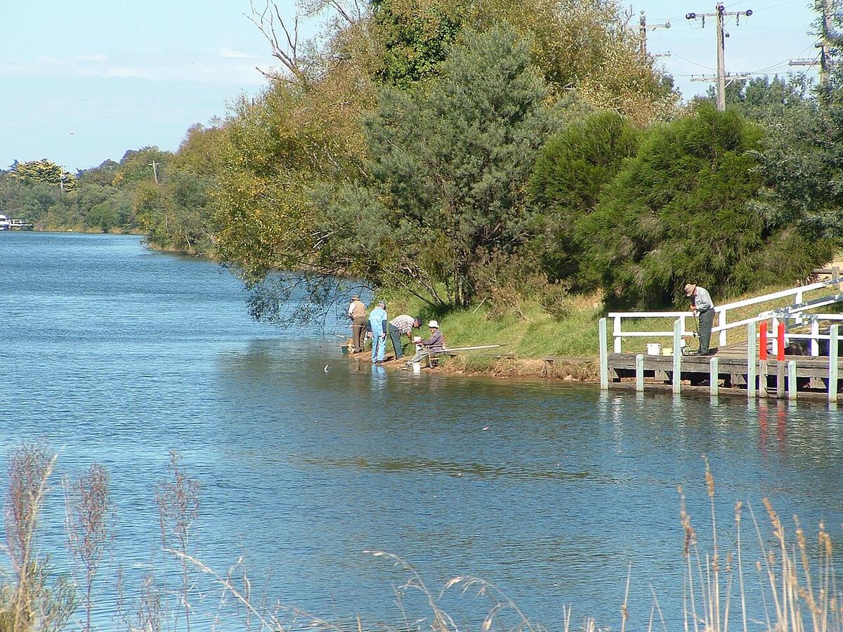 The Mitchell River near the Princes Highway bridge in Bairnsdale, with anglers on the bank and a jetty