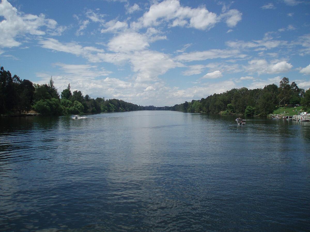 The Nepean River at Penrith, New South Wales, a wide reach between tree-lined banks under a blue sky